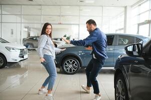 Happy young couple chooses and buying a new car for the family. Visitting the dealership photo