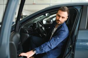 Young man is choosing a new vehicle in car dealership photo