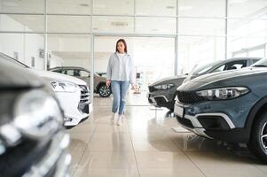 contento mujer cliente hembra comprador cliente escoger auto querer a comprar nuevo automóvil en coche sala de exposición foto