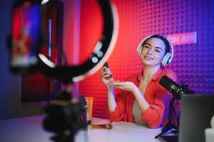 Beauty blogger woman filming daily make-up routine tutorial near camera on tripod photo