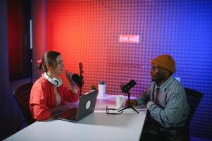 two radio hosts in headphones laughing while recording podcast in studio together photo