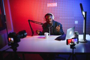 hermoso joven africano americano hombre hablando dentro micrófono mientras grabación radio espectáculo foto