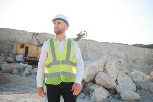 Worker in hardhat standing in stone quarry photo