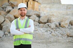 Worker in hardhat standing in stone quarry photo