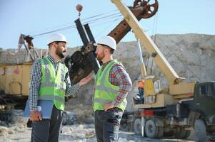 Portrait of stone quarry workers standing on the background of an excavator photo