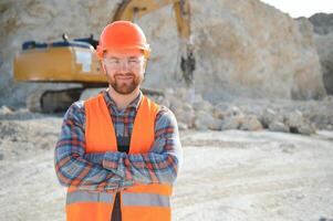 Worker in hardhat standing in stone quarry photo