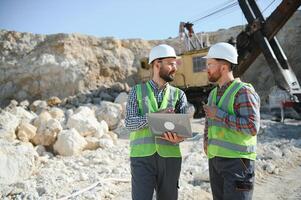 Portrait of stone quarry workers standing on the background of an excavator photo