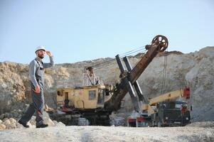 Worker in hardhat standing in stone quarry photo