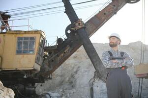 Worker in hardhat standing in stone quarry photo