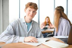 estudiantes sentar a compartido escritorio haciendo notas estudiando juntos a Universidad foto