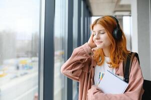 estudiante niña con libros y un mochila escucha a música en auriculares foto