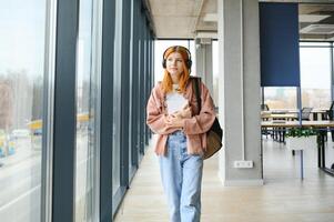 estudiante niña con libros y un mochila escucha a música en auriculares foto