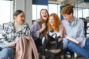 A group of cheerful student friends are sitting on the floor in a classroom photo