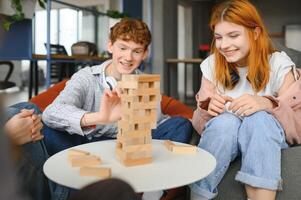 The company of young people plays a table game called jenga photo
