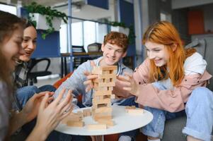 The company of young people plays a table game called jenga photo