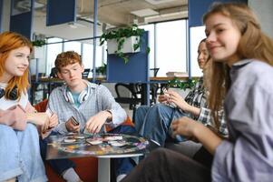 Group of creative friends sitting at wooden table. People having fun while playing board game photo