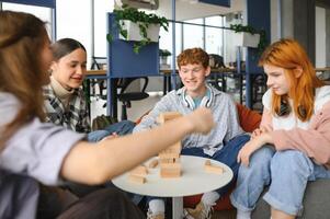 Group of creative friends sitting at wooden table. People having fun while playing board game photo