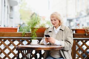 Fashion portrait of young woman siting at the table with cup of coffee, tea in street cafe. photo