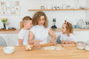 An attractive smiling family of mother, and two children, boy, girl, son, daughter cookies in a kitchen at home photo