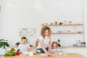 An attractive smiling family of mother, and two children, boy, girl, son, daughter cookies in a kitchen at home photo