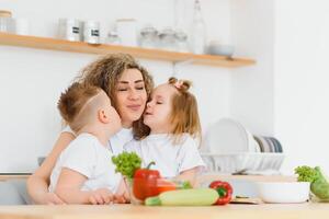 Young mother and her two kids making vegetable salad photo