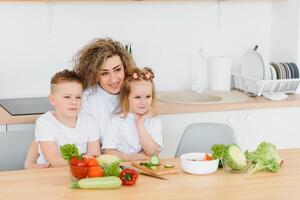 mother with children preparing vegetable salad at home photo