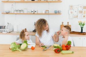familia en un cocina. hermosa madre con niños. dama en blanco blusa. foto