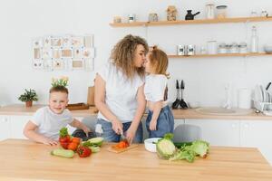 Young mother and her two kids making vegetable salad photo