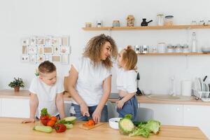 mother with children preparing vegetable salad at home photo