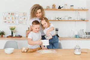 An attractive smiling family of mother, and two children, boy, girl, son, daughter cookies in a kitchen at home photo