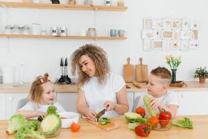 Young mother and her two kids making vegetable salad photo