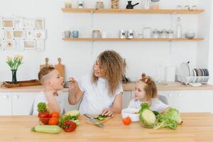 familia en un cocina. hermosa madre con niños. dama en blanco blusa. foto