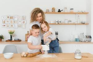 Family learning new recipe together. Happy mom and kids mixing ingredients for homemade cake, pie or cookie dough in the kitchen. photo