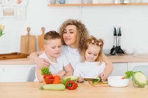 mother with children preparing vegetable salad at home photo