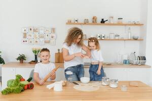 An attractive smiling family of mother, and two children, boy, girl, son, daughter cookies in a kitchen at home photo