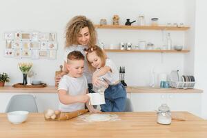 happy family in the kitchen. mother and children preparing the dough, bake cookies photo