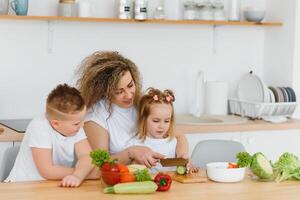 mother with children preparing vegetable salad at home photo