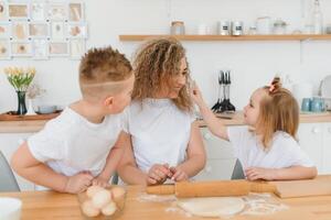 An attractive smiling family of mother, and two children, boy, girl, son, daughter cookies in a kitchen at home photo