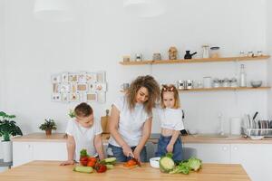 Family in a kitchen. Beautiful mother with children. Lady in white blouse. photo