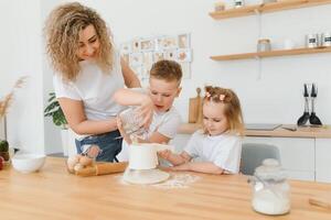 contento familia en el cocina. madre y niños preparando el masa, hornear galletas foto