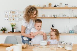 contento familia en el cocina. madre y niños preparando el masa, hornear galletas foto