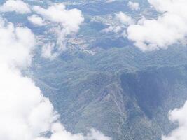 Aerial view of mountains, sky, and clouds seen through the airplane window photo