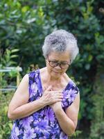 retrato de un mayor mujer teniendo un corazón ataque. un mayor mujer agarrando su cofre en dolor a el primero señales de angina de pecho o miocárdico infarto o corazón ataque. corazón ataque concepto foto