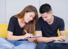 un joven Pareja trabajando juntos mientras sentado en un sofá en el oficina. negocio éxito desde trabajo juntos como un equipo. concepto de negocio y comercio electrónico foto