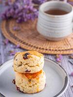 Close-up of traditional British scones dessert on a plate with a teacup and flower blurred background. Space for text. Concept of dessert and tea photo