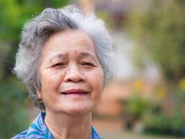 Portrait of elderly woman with short white hair and standing smile in garden. Asian senior woman healthy and have positive thoughts on life make her happy every day. Health care concept photo