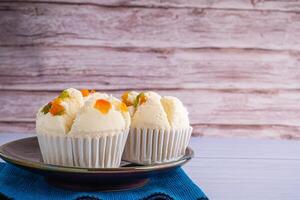 Side view of Thai steamed cupcakes topped with dry fruit on a plate placed on a blue cloth with wooden wall background. Khanom Pui Fai in Thai photo