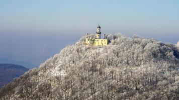 Aerial view of Milesovka mountain's peak with a building and frosted trees photo