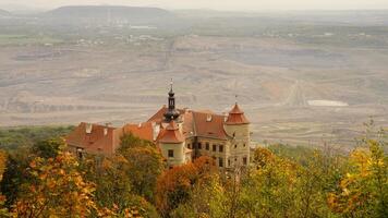 Historic castle surrounded by autumn trees with a quarry in the background photo