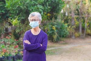 retrato de un mayor mujer con corto blanco cabello, vistiendo un cara máscara para proteger virus, COVID-19, coronavirus, bacterias, polen granos, aire contaminación pm 2.5, y más. cuidado de la salud concepto foto